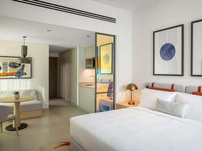 Modernes Hotelzimmer mit Doppelbett, Sofa, Kunstwerken an den Wänden und indirekter Beleuchtung.