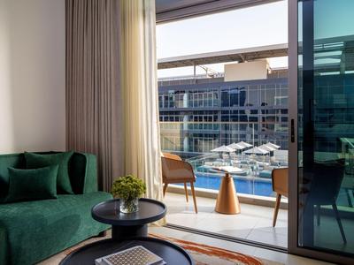 Balkon mit zwei Stühlen und Blick auf einen Yachthafen, innen grünes Sofa und Tische.