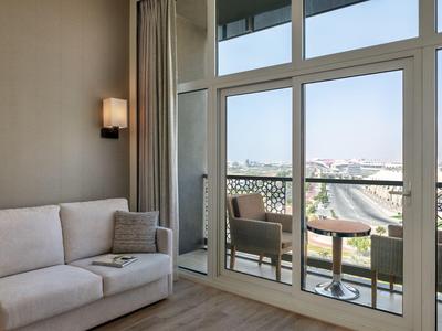 Modernes Hotelzimmer mit Sofa und Balkon mit Stühlen und Ausblick auf Stadt und Berge.