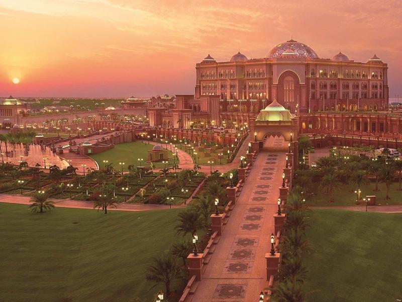 Magnificent hotel at sunset with manicured garden and illuminated pathway.