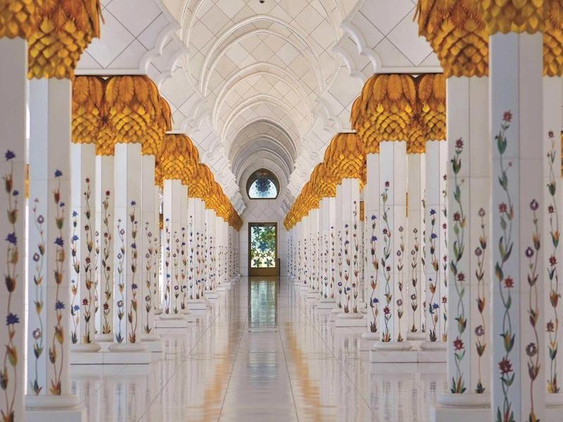 Elegant corridor with white columns and golden details in a luxury hotel hall.