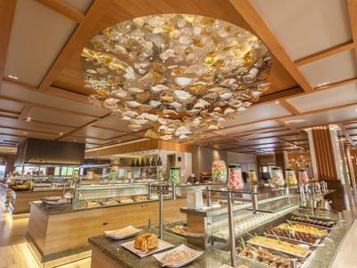 Buffetbereich in hellem Restaurant mit Holzdecke und großer, runder Lampeninstallation.