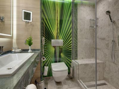 Modernes Bad mit grauen Fliesen, grüner Pflanzenwand hinter Toilette und Glasdusche.