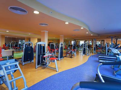 Nowoczesna siłownia z urządzeniami treningowymi i bieżniami w jasnym otoczeniu.