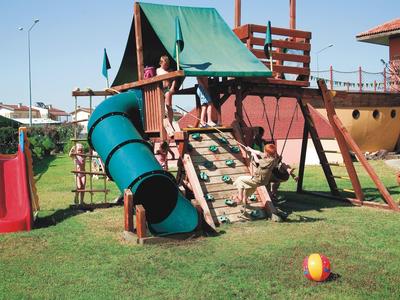 Kinderspielplatz mit Klettergerüst, Rutsche, Tunnelrutsche und buntem Ball auf grünem Rasen.