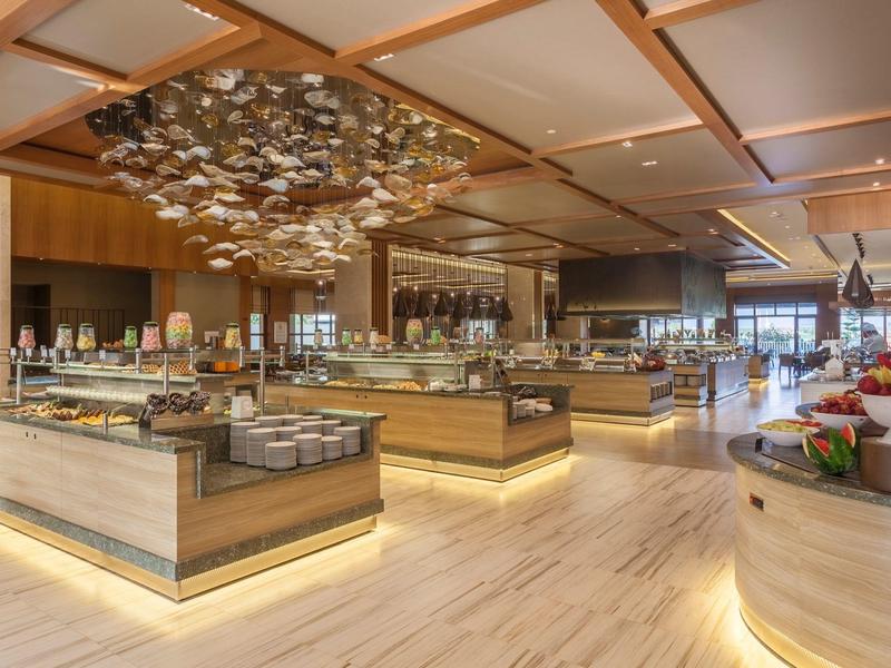 Großer, moderner Buffetraum mit hellem Holz, Glasvitrinen und dekorativer Deckenbeleuchtung.