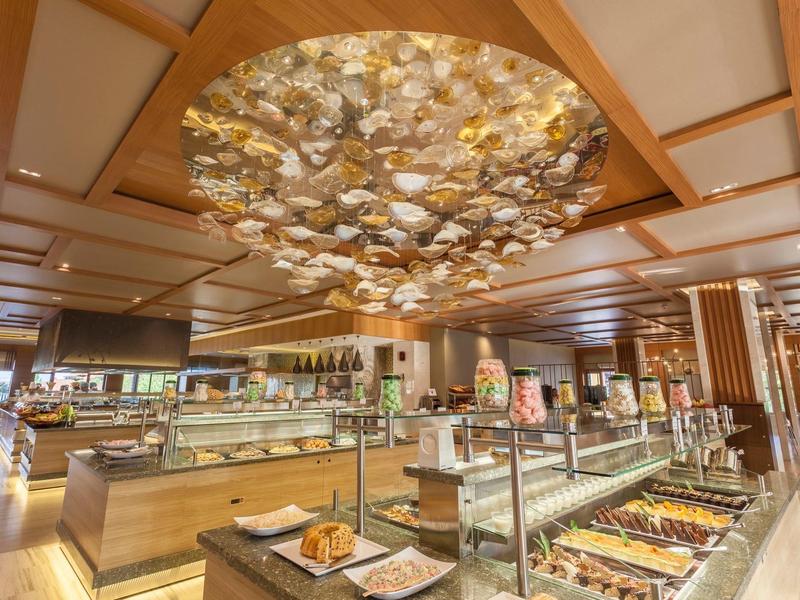 Buffetbereich in hellem Restaurant mit Holzdecke und großer, runder Lampeninstallation.