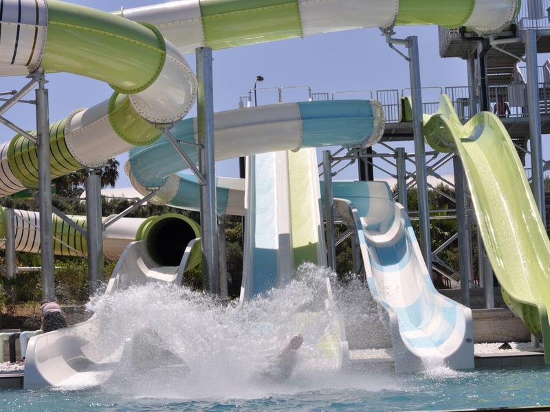 Wasserrutschen in Grün, Blau und Weiß mit spritzendem Wasser im Schwimmbecken.