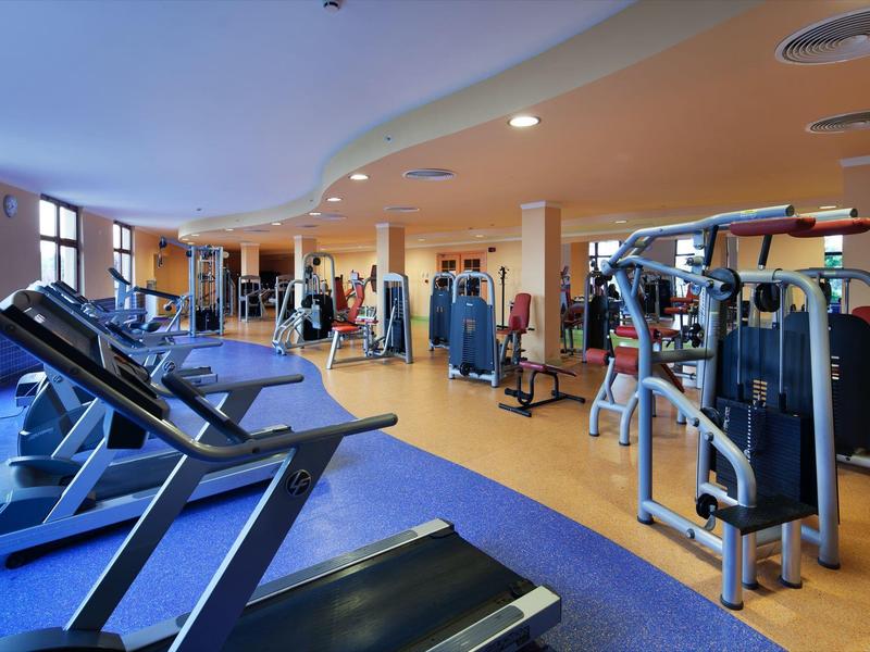 Moderne Fitnessstudio mit Laufbändern, Kraftgeräten und hellem, offenen Raum.