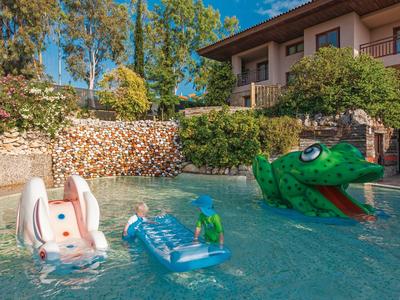 Ein Gartenpool mit aufblasbarem Krokodil, Hasenrutsche und blauem Luftmatratze unter Bäumen.