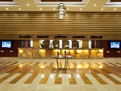 Hotel-Lobby mit modernem Empfangstresen, beleuchteten Natursteinplatten und glänzendem Boden.