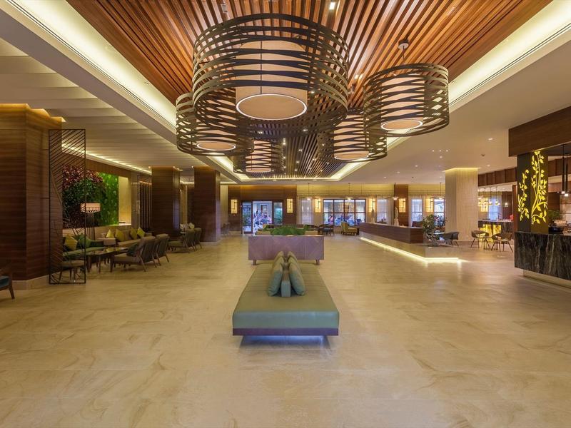 Ruime hotel lobby met moderne zithoeken en decoratieve plafondverlichting.