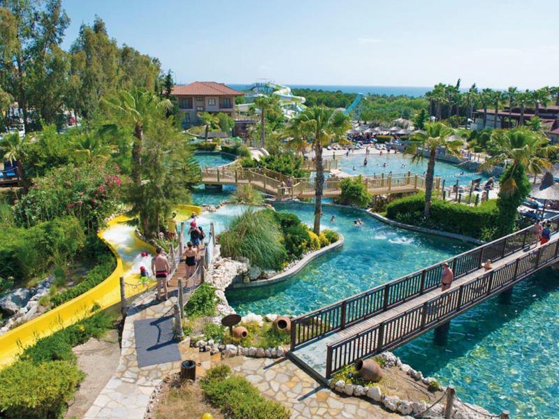 Resort met weelderige tuinen, zwembaden, wandelpaden en gasten die van een zonnige dag genieten.