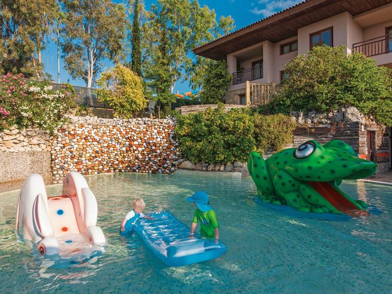 Zwembad met drijfspeelgoed zoals een krokodil, een konijn en een ligstoel bij een hotel.
