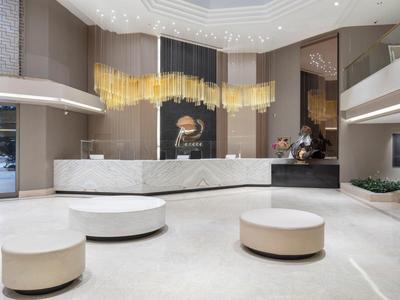 Helle Hotellobby mit runden Sitzgelegenheiten, glatten Marmorböden und moderner Deckenbeleuchtung.