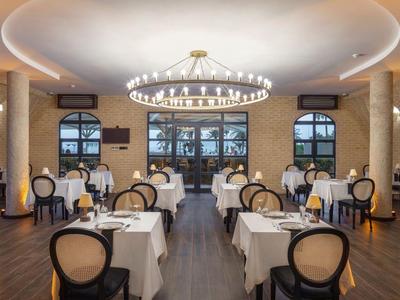 Elegantes Restaurant mit runden Säulen, Kronleuchtern und Tischen mit weißen Tischdecken.