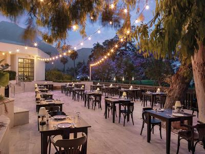 Gemütlicher Außenbereich eines Restaurants mit Lichterketten und Blick auf Berge.