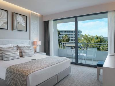 Habitación de hotel moderna con cama doble, dos obras de arte, puertas a la terraza y vista a la piscina.