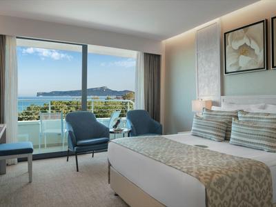 Modernes Hotelzimmer mit Doppelbett, Balkon und Blick auf das Meer und die Berge.