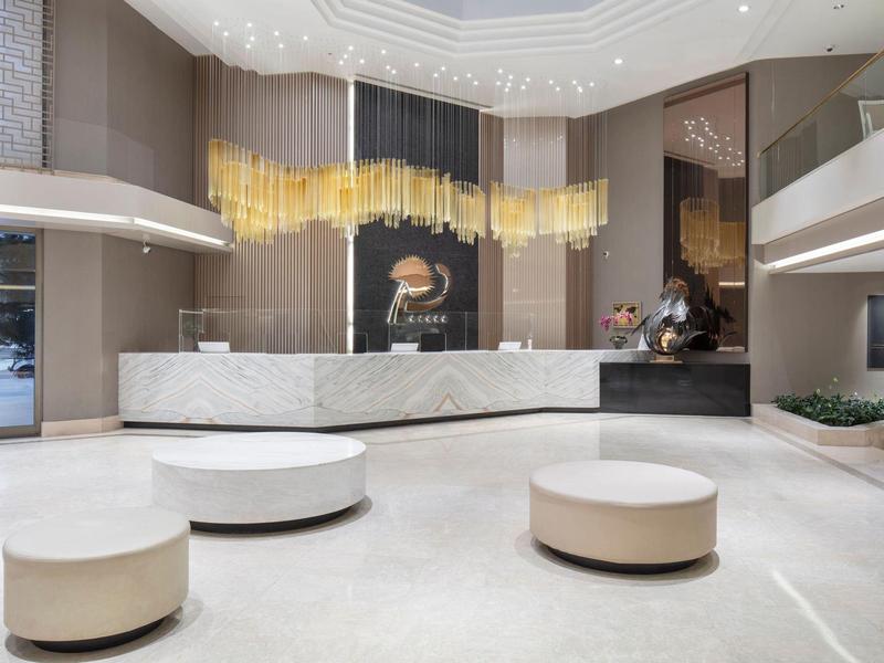 Helle Hotellobby mit runden Sitzgelegenheiten, glatten Marmorböden und moderner Deckenbeleuchtung.