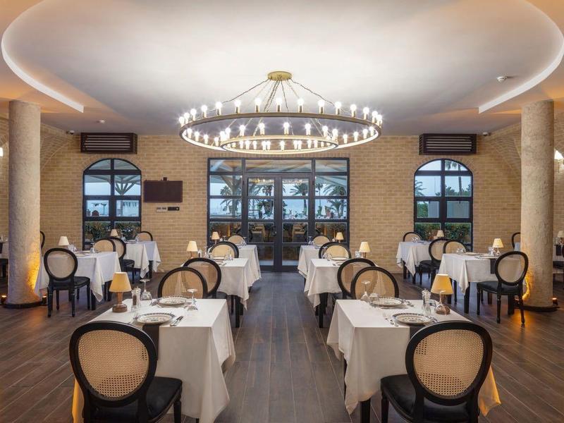 Elegantes Restaurant mit runden Säulen, Kronleuchtern und Tischen mit weißen Tischdecken.