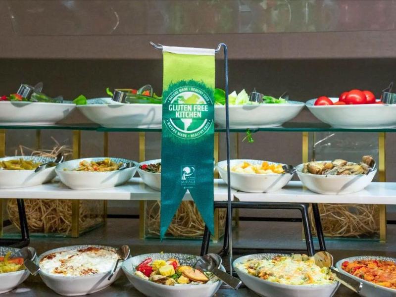 Buffet mit verschiedenen frischen Salaten und Gemüse in weißen Schalen auf zweistufiger Ablage.