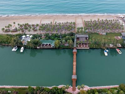 Vue aérienne d'un hôtel avec un quai privé et des bateaux sur une rivière près d'une plage de sable.