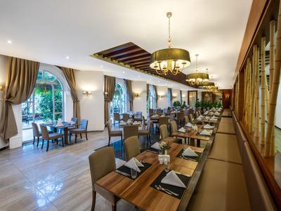 Restaurant élégant avec mobilier en bois, grandes fenêtres et lustres dorés.