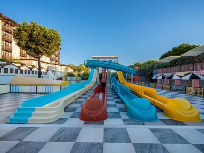 Plusieurs toboggans aquatiques colorés dans une zone de piscine vide d'un hôtel sous un ciel dégagé.