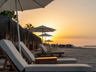 Chaises longues vides sous des parasols sur la plage au coucher du soleil.