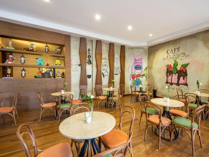 Intérieur de café chaleureux avec des tables rondes, des chaises en bois et des décorations murales colorées.