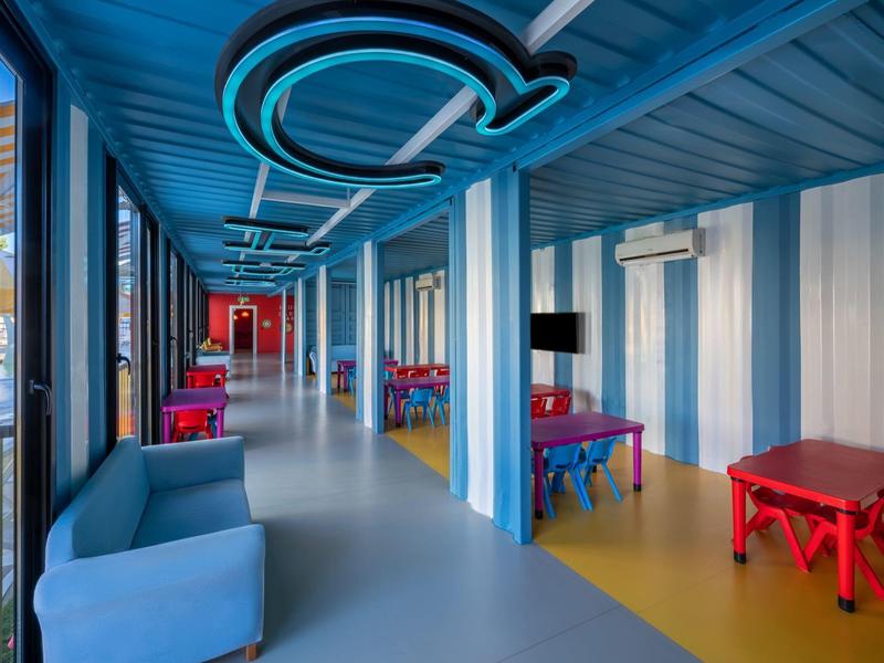 Couloir d'hôtel moderne avec mobilier coloré et murs et plafond bleus et blancs.