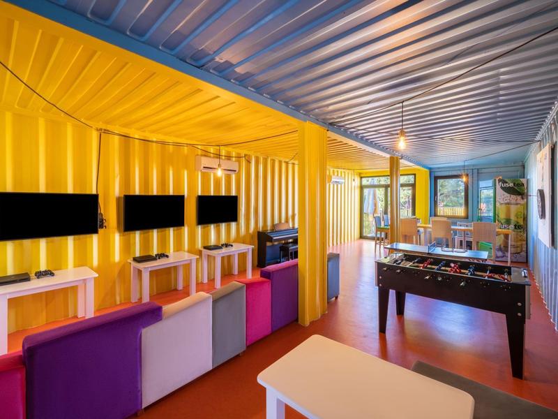 Salon moderne avec murs colorés, téléviseurs et baby-foot dans un hôtel.