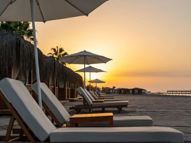 Chaises longues vides sous des parasols sur la plage au coucher du soleil.