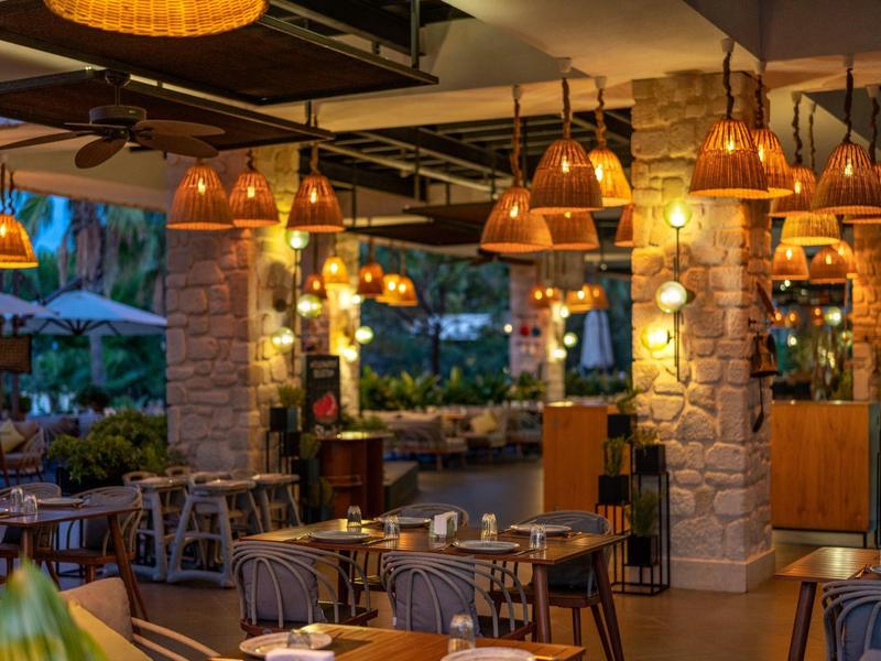 Restaurant extérieur confortable et bien éclairé avec mobilier en bois et lumières chaudes suspendues.
