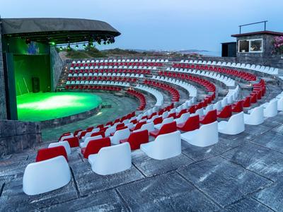 Beleuchtetes Amphitheater mit roten und weißen Sitzen im Freien bei Dämmerung.