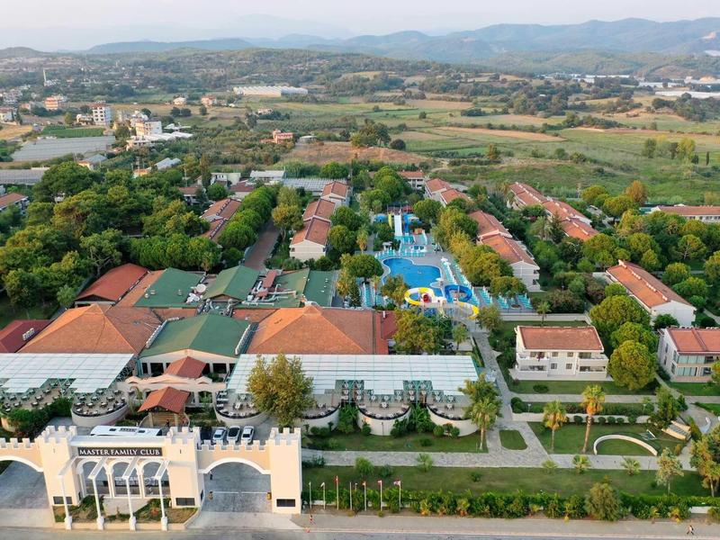 Luftaufnahme einer weitläufigen Anlage mit Gebäuden, Pools, Gärten und umgebender Landschaft.