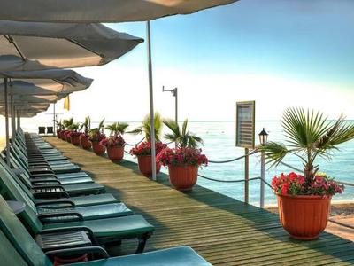 Terrasse d'hôtel avec chaises longues et passerelle en bois décorée de fleurs au bord de la mer