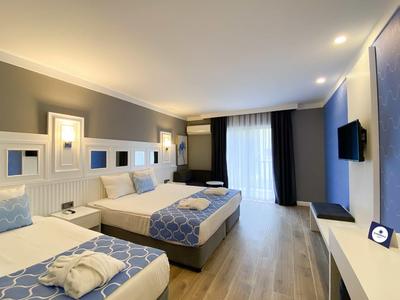 Modernes Hotelzimmer mit zwei Betten, TV und großem Fenster mit Vorhängen.