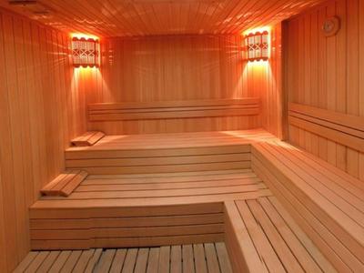 Vue intérieure d'un sauna en bois avec des bancs et un éclairage chaleureux.