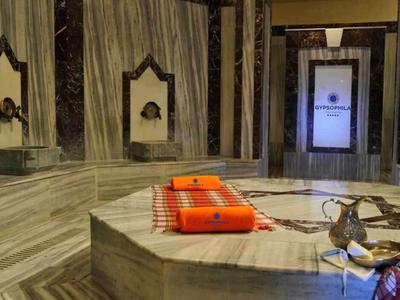 Intérieur avec sols et murs en marbre, table centrale avec serviettes orange et accessoires traditionnels.