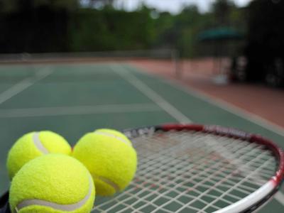 Nahaufnahme von Tennisbällen auf einem Tennisschläger vor einem Tennisplatz