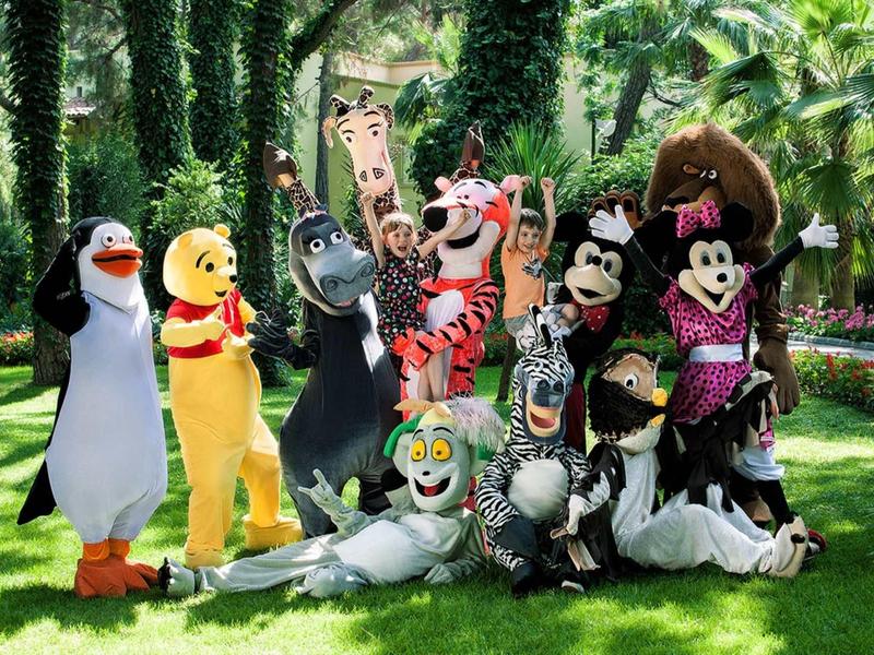 Plusieurs personnages en costumes colorés posent à l'extérieur sur une pelouse verte.