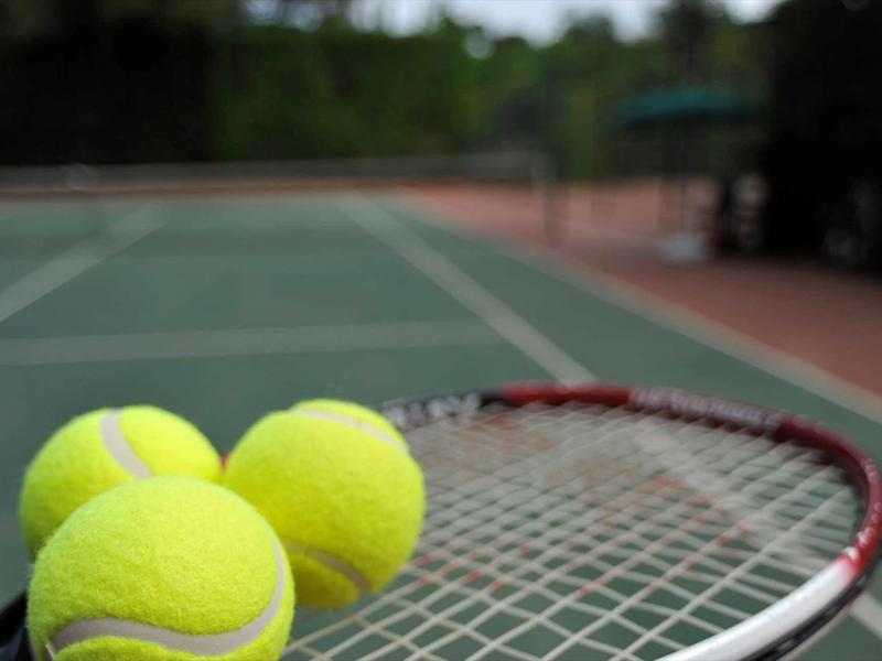 Gros plan de trois balles de tennis sur une raquette sur un court de tennis.
