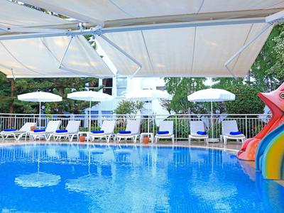 Outdoor-Pool mit Wasserrutsche und Liegestühlen unter Sonnenschirmen in einem Hotelgarten.