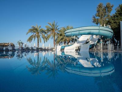 Wasserrutsche am Pool mit Palmen im Hintergrund unter klarem Himmel.