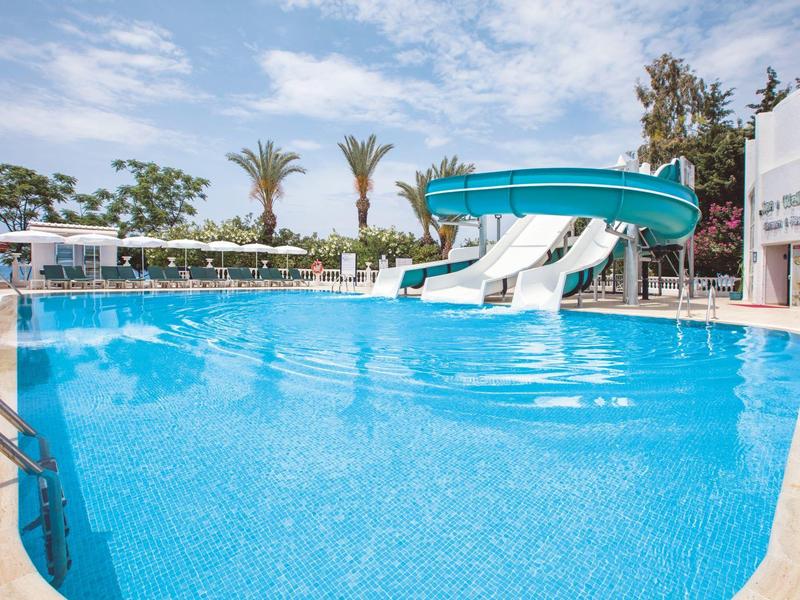 Blick auf einen Pool mit Wasserrutschen und Palmen an einem sonnigen Tag.