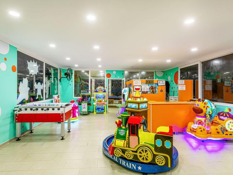 Bunter Kinderspielbereich mit Spielzeug, Tischfußball und gemütlicher Beleuchtung in einem Innenraum.