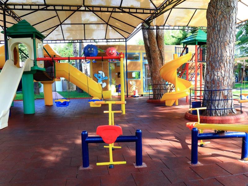 Bunter Kinderspielplatz mit Rutschen, Schaukeln und Klettergerüsten unter einem Sonnenschutz