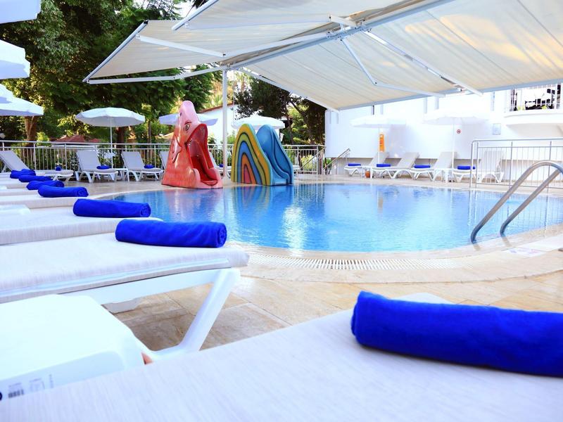 Poolbereich mit Liegestühlen und bunten Wasserrutschen unter Sonnenschirmen.